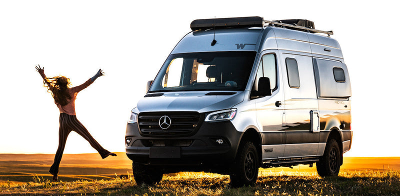 Person happily jumping in front of a Sprinter van